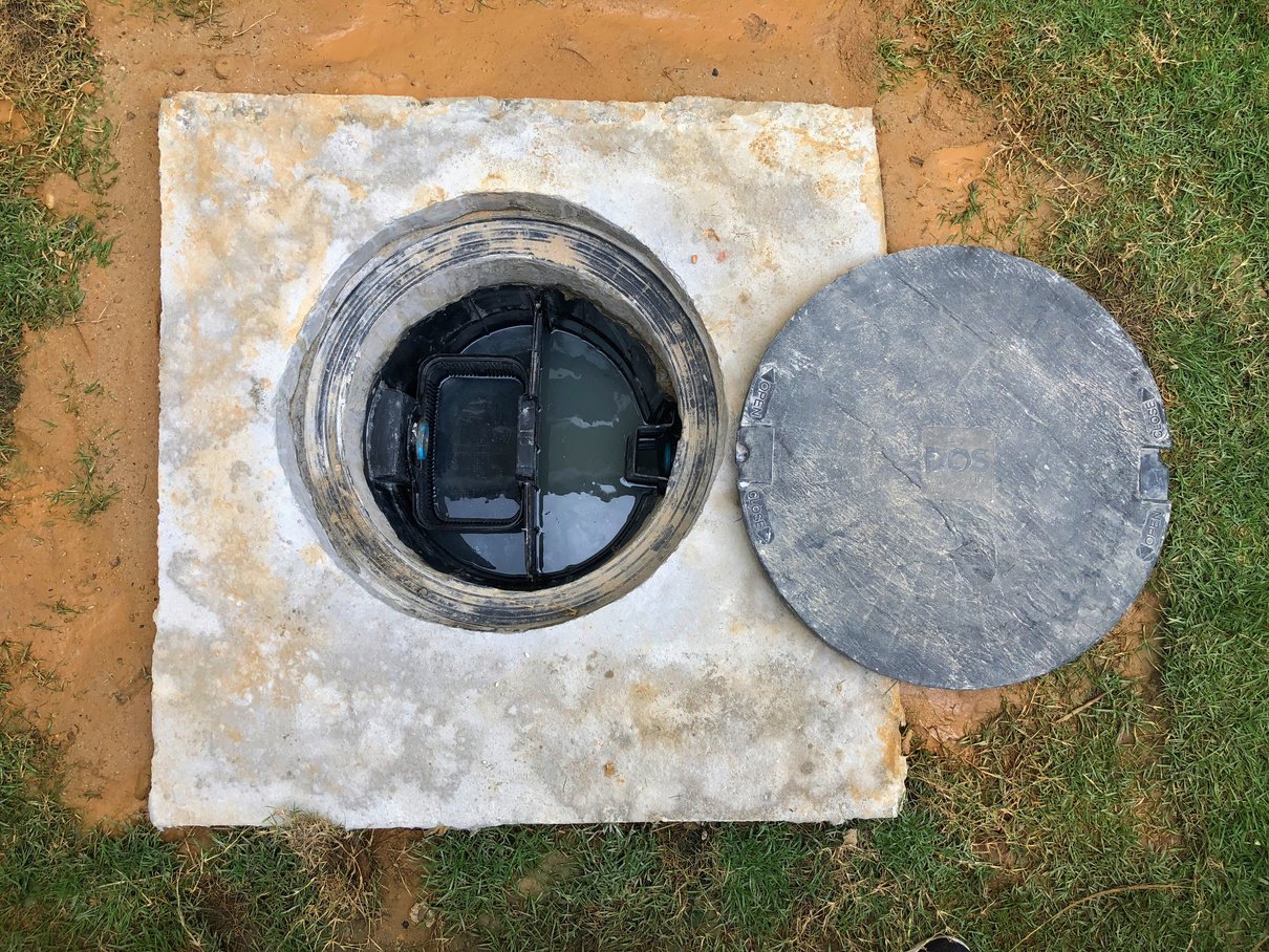 A hole of grease trap underground tank with the drain system around the house.